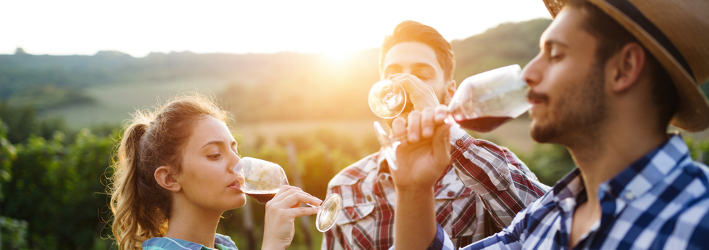 Two men and one woman sample wine