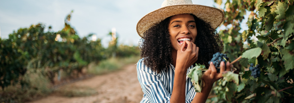 Woman eats grapes off of a vine