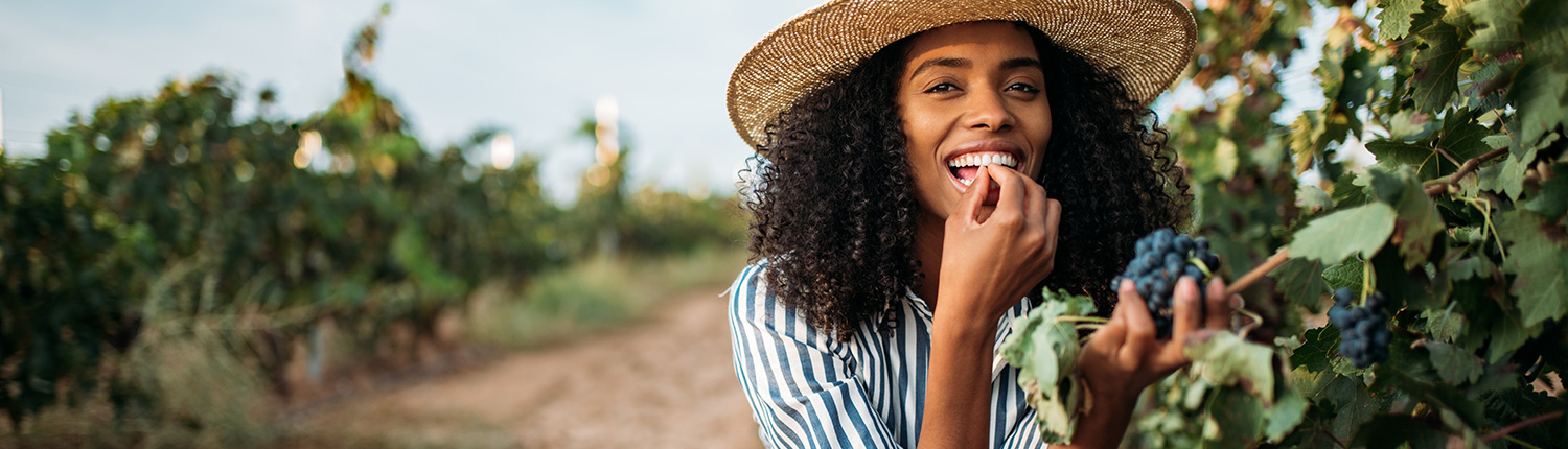 Woman eats grapes off of a vine